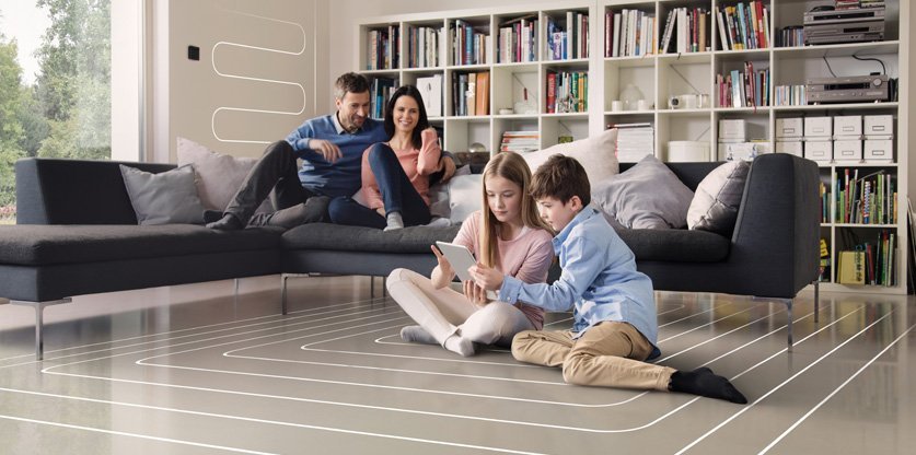 Eine Familie die in einem Wohnzimmer ist, in dem die Kinder auf dem Boden sitzen